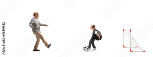 Boy and grandfather playing football in front of a mini goal