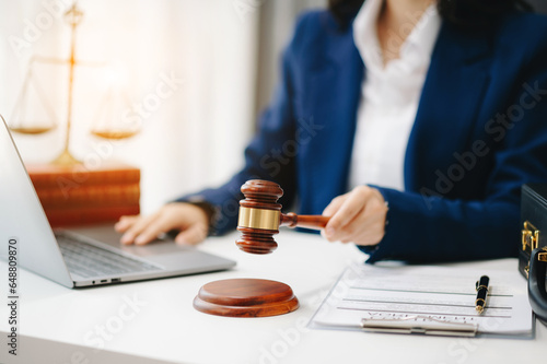 justice and law concept.law theme wooden desk, books, balance. Male judge in a courtroom the gavel,working with digital tablet computer on desk.