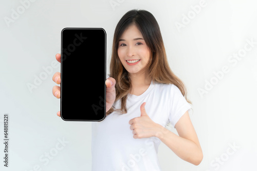 beautiful Asian young woman showing big smart phone with blank screen , black screen empty copy space for advertising banner isolated on white background , Mock Up Image © suphaporn