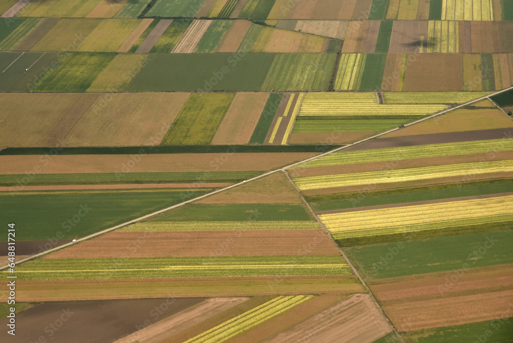 The view of the agricultural fields from the plane window. Agriculture colorful fields in the late summer. Abstract color texture background.

