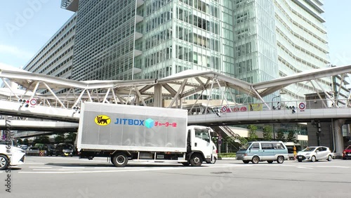 OSAKA, JAPAN - JULY 2023 : View of road traffic at the intersection and tall building. Time lapse shot in daytime. Japanese business, finance and real estate concept video. photo