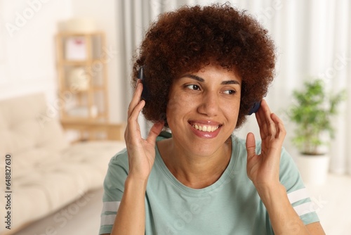 Happy young woman in headphones enjoying music indoors