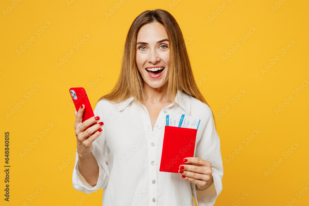 Traveler woman wear white casual clothes hold passport ticket mobile cell phone isolated on plain yellow background . Tourist travel abroad in free time rest getaway. Air flight trip journey concept. Traveler woman wear white casual clothes hold passport ticket mobile cell phone isolated on plain yellow background . Tourist travel abroad in free time rest getaway. Air flight trip journey concept.