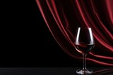 A glass of red wine and a silk curtain on a black background