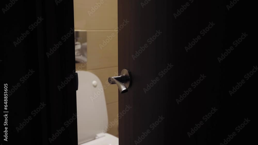 The door of the toilet or bathroom is slightly ajar. The toilet and tile are visible through the ...