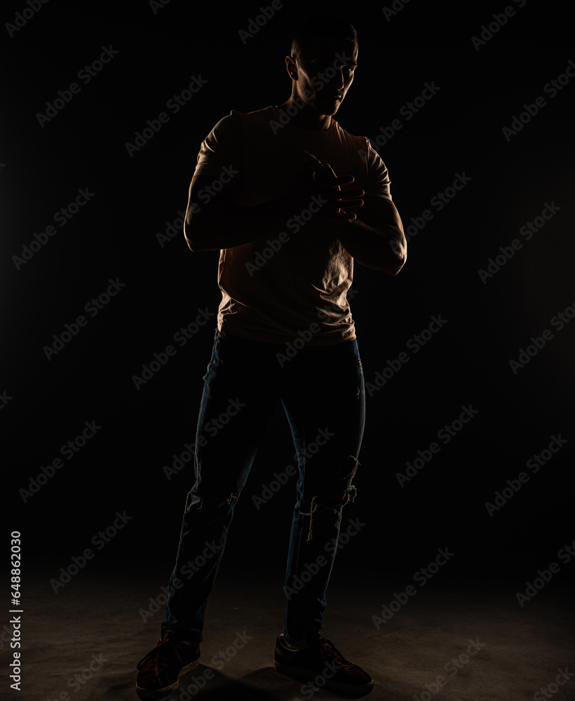 Silhouette of a guy posing in studio while standing and thinking