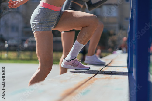 Close up shot of sportsgirls doing jumps on bench, exercising their legs