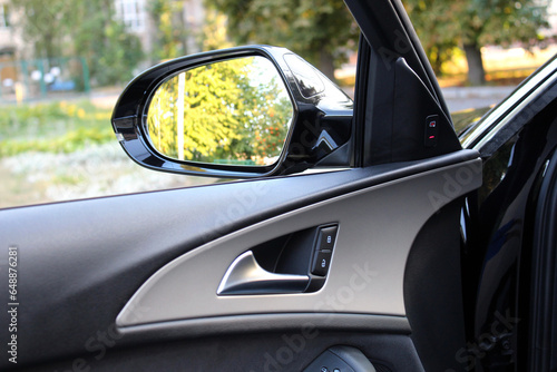 Rear view mirror from car window.  Look in the rear view mirror of a car. Door handle with power window control. © Best Auto Photo