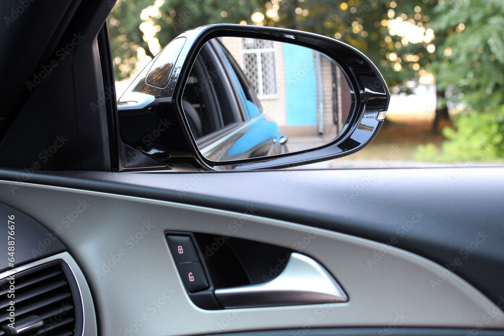 Rear view mirror from car window.  Look in the rear view mirror of a car. Door handle with power window control.