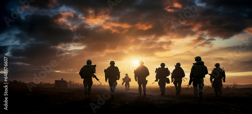 A group of military men move beyond the horizon at sunset.