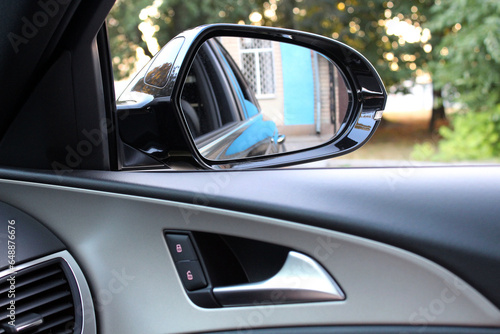 Rear view mirror from car window. Look in the rear view mirror of a car. Door handle with power window control.