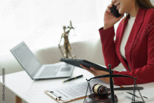 Attorney's office. Goddess of justice with scales and lawyer working on laptop Law, advice and justice concept Lawyer reads contract Young female lawyer or lawyer working in the office