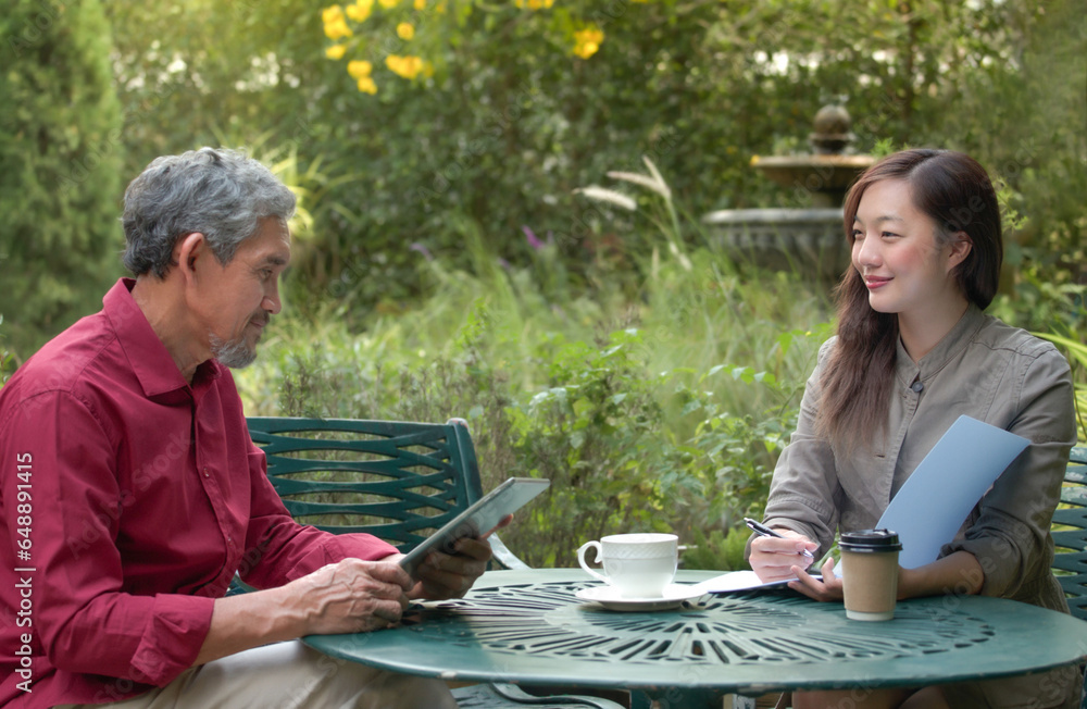 businesswoman or freelance working outside office,a young female real estate agent or health insurance agent present job by tablet  to senior pensioner customer before sign a contract at home outdoors