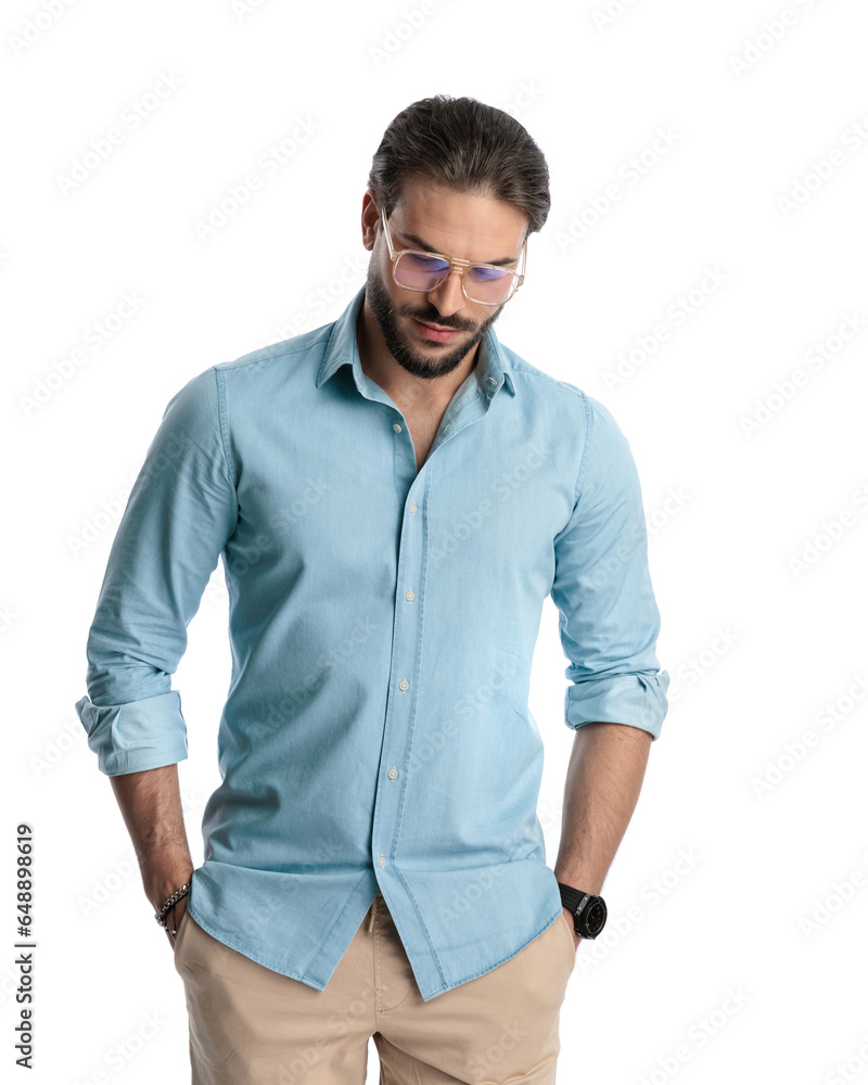sexy bearded man with glasses holding hands in pockets and looking down sexy bearded man with glasses holding hands in pockets and looking down