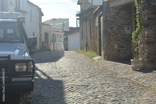 Stone houses and left side of a parked car in the street stone