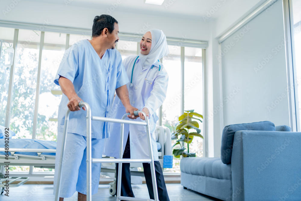 A Muslim Female doctor help a patient who is doing physical therapy and is practicing walking with a walking stick. A Muslim Female doctor help a patient who is doing physical therapy and is practicing walking with a walking stick.