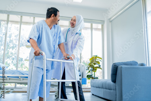 A Muslim Female doctor help a patient who is doing physical therapy and is practicing walking with a walking stick.