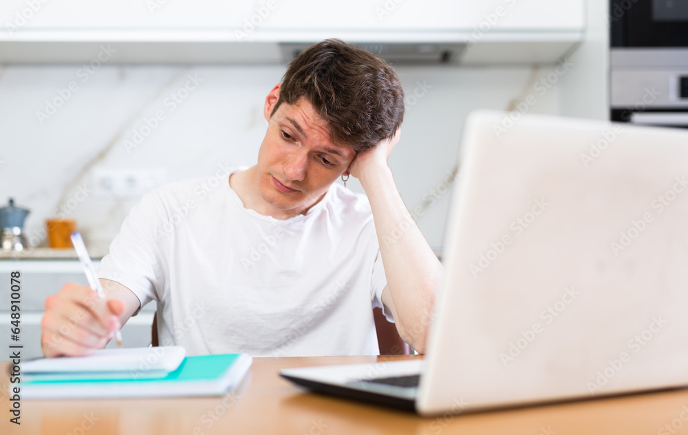 Young guy studying at home with laptop Young guy studying at home with laptop