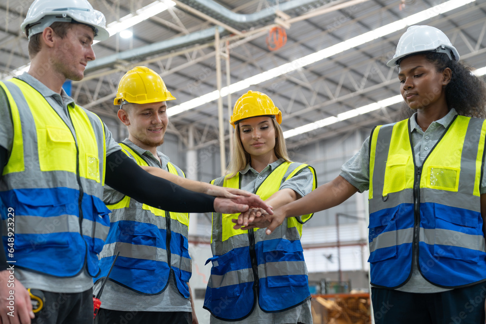 Group of Engineer and workers wear safety vests with helmets join hands to collaborate with team working in factory Group of Engineer and workers wear safety vests with helmets join hands to collaborate with team working in factory