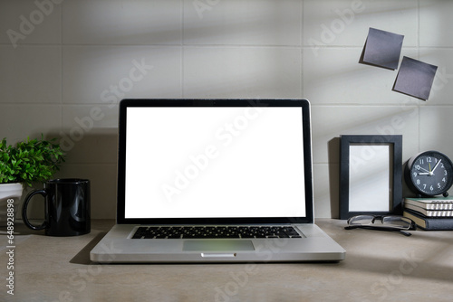 Mockup computer laptop, coffee cup, alarm clock and ceramic vase on white table.
