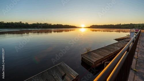 Wide Angle Timelapse of Sunrise over a river. High-quality 4k footage shows fog forming low on the water as well as higher in the atmosphere in the distance.  photo