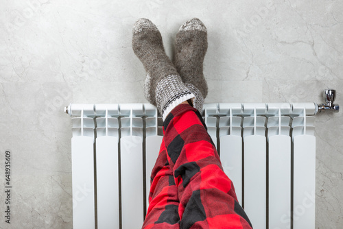 Φωτογραφία Legs on a radiator against the background of a light wall