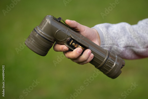 A hand with a green military flashlight. A flashlight for lighting in a hiking trip.