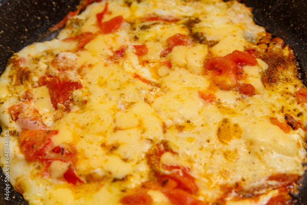 Fried eggs with tomatoes and sprinkled with cheese in a frying pan close-up Fried eggs with tomatoes and sprinkled with cheese in a frying pan close-up