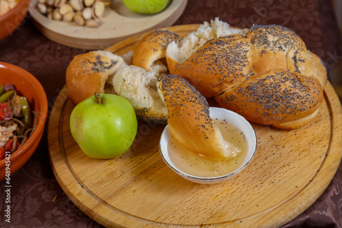 Festive set table for Rosh Hashanah with ritual treats honey challah apple on brown tablecloth.