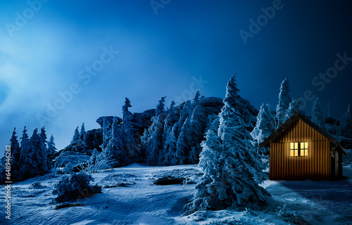 Weihnachtshütte mit leuchtendem Fenster in einer verschneiten Winterlandschaft