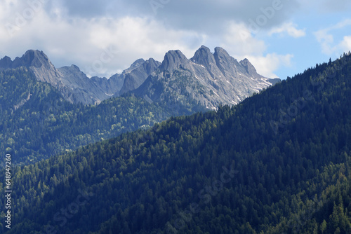 The picture depicts a breathtaking mountain landscape in the Caucasus Mountains of Russia. Towering peaks are adorned with coniferous forests..