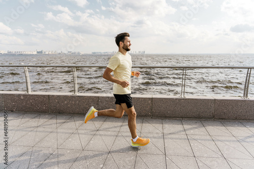 Motivation and an active lifestyle in the city. The trainer is a strong man fitness in comfortable outdoor sportswear. Runner active interval training and warm-up. photo