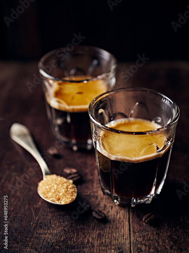 Two glasses of intense espresso coffee on rustic wooden background. Close-up. Copy space