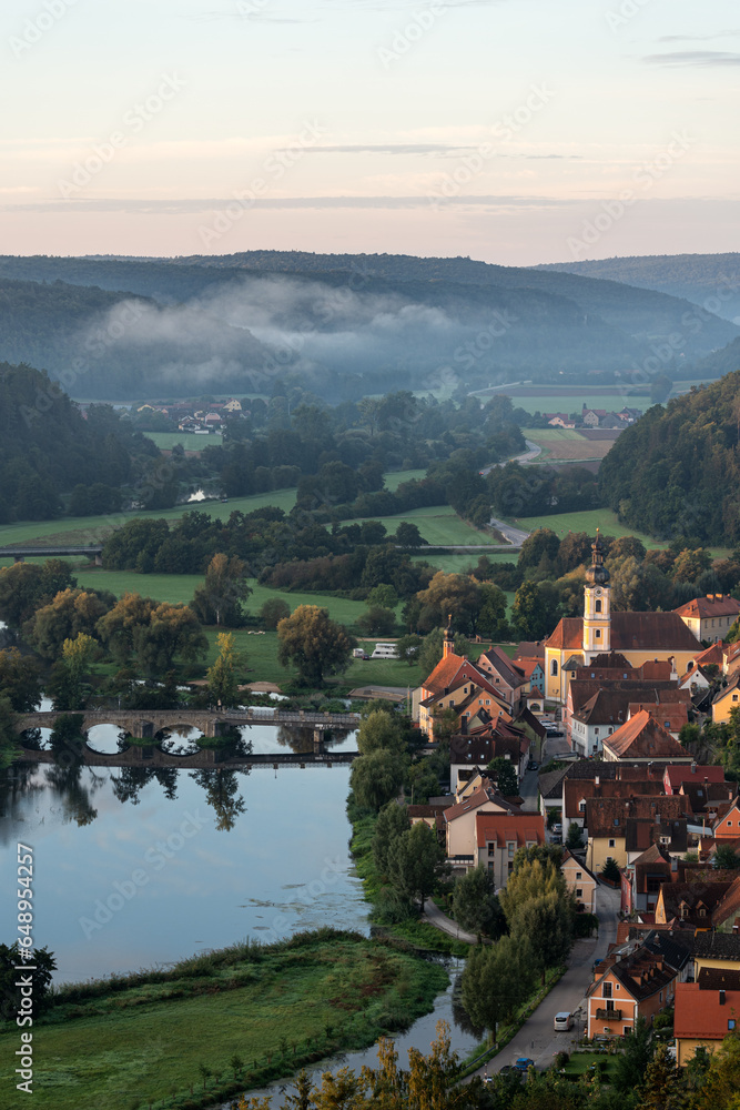 Kleines Dorf in Bayern an einem Fluss zum Sonnenaufgang mit Nebel und Kirche. Kallmünz.