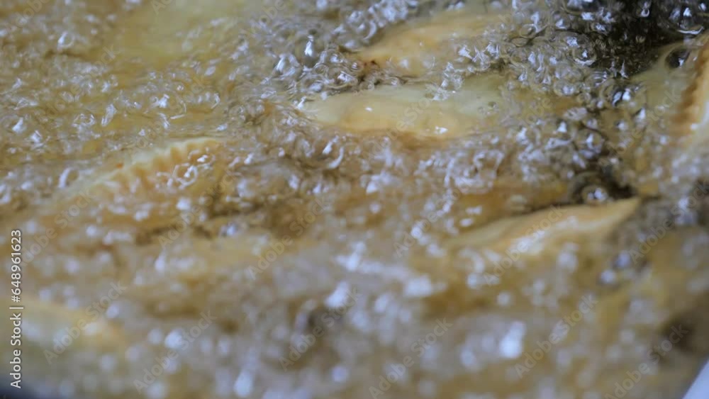 The process of frying chebureks in boiling oil. Pasties with meat fried in sunflower oil, deep-fried. Pie or cheburek is deep-fried. The process of frying chebureks in boiling oil. Pasties with meat fried in sunflower oil, deep-fried. Pie or cheburek is deep-fried.