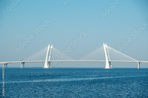 White concrete cable-stayed bridge on supports across the bay.