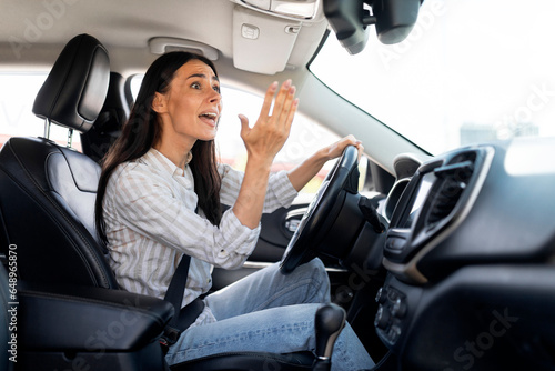 Woman driver stuck in traffic jam gesturing with hand, screaming
