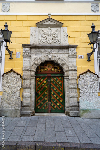 Door of the house of the Blackheads in the city of Tallinn, on a cloudy day. Green door with yellow details.