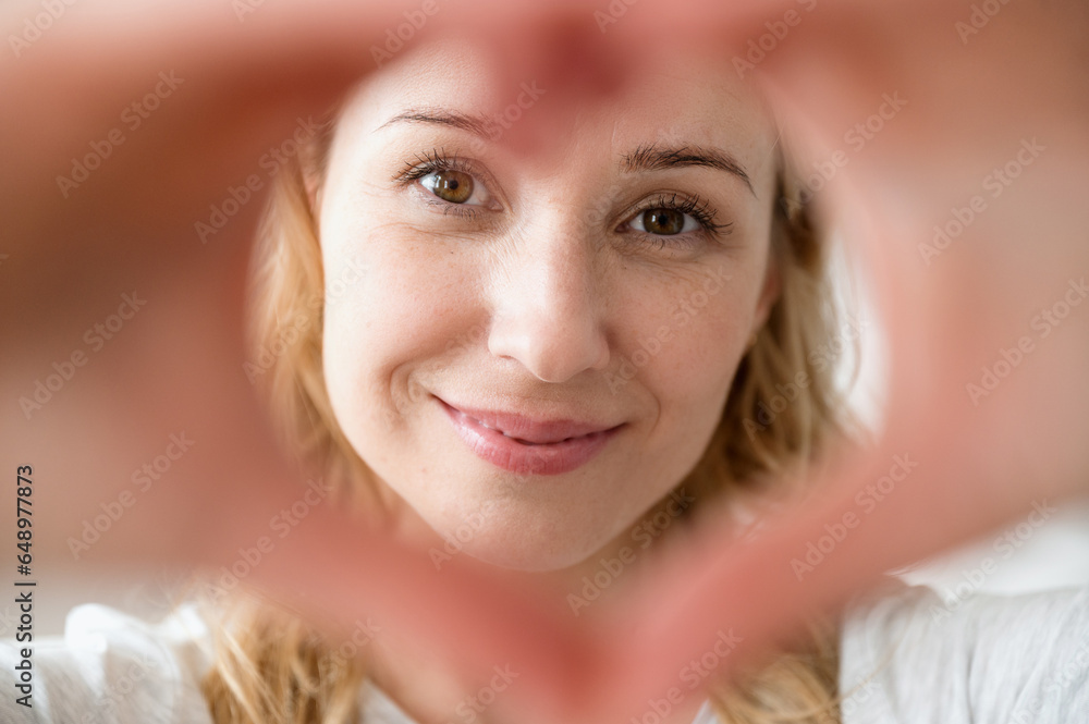 Close up portrait of smiling woman making love gesture Close up portrait of smiling woman making love gesture