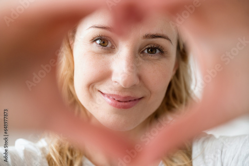 Close up portrait of smiling woman making love gesture