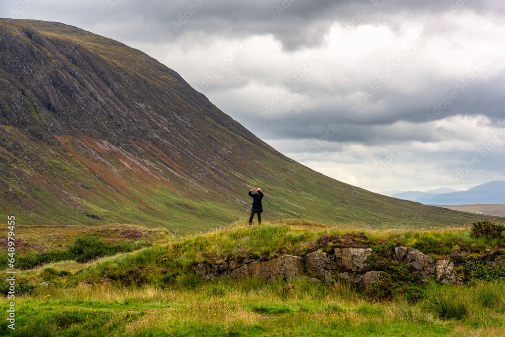 Obraz premium A woman taking pictures of the wonderful mountain scenery of the Glencoe Valley, Scotland.