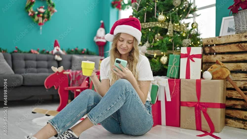 Young blonde woman using smartphone drinking coffee celebrating christmas at home Young blonde woman using smartphone drinking coffee celebrating christmas at home