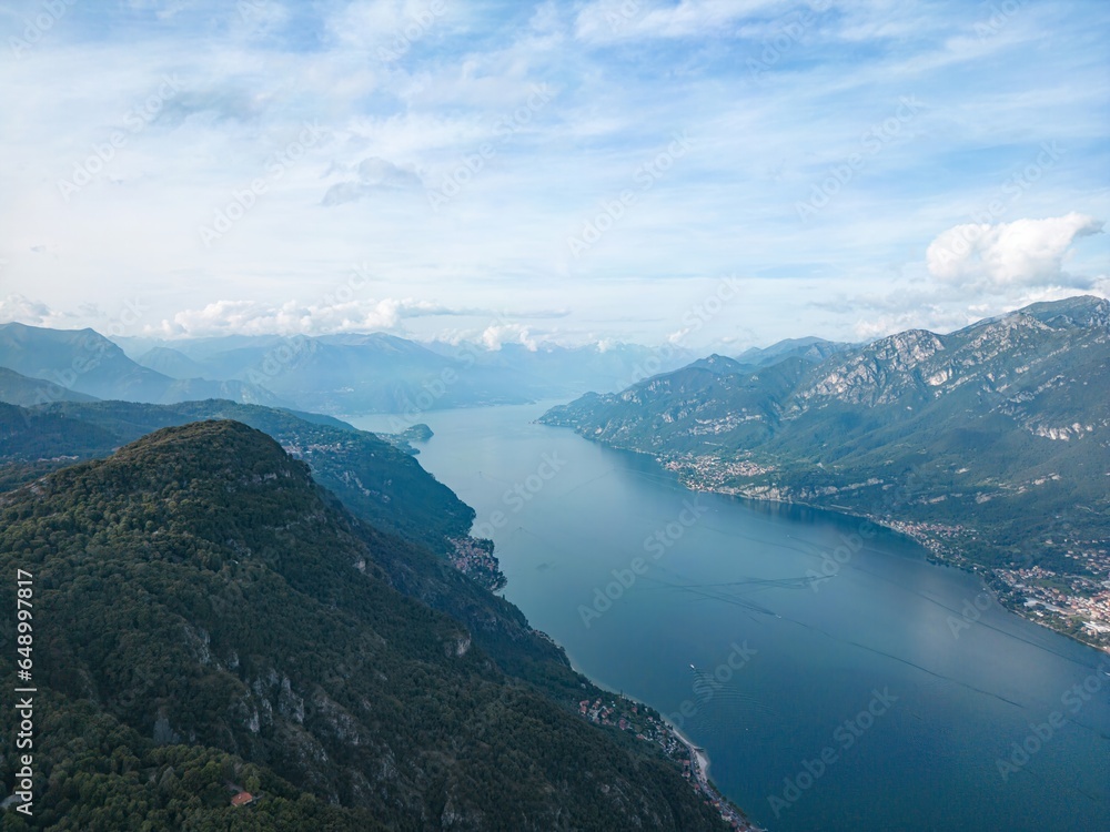 Lake Como's beauty captured aerially near Lecco. Mountains and gentle clouds complement the tranquil scene