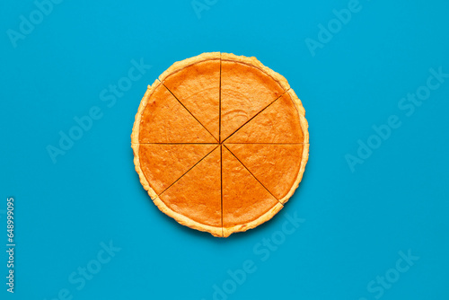 Sliced pumpkin pie, top view on a blue table