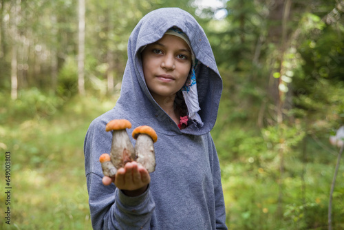A European girl holds boletus mushrooms in her hands.