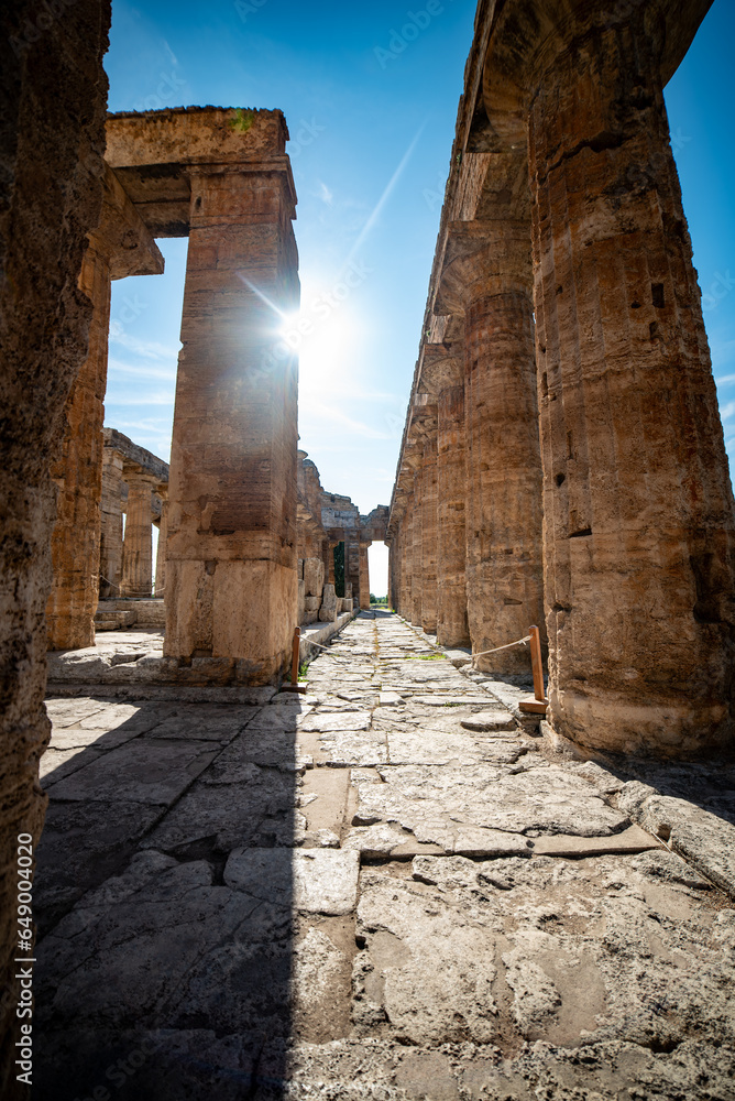 Ancient greek temples located in Italy in Peastum, Salerno with columns and blue sky and sun background