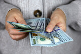 Woman in sweater counts US dollars, female hands close up. Person with money, concept of salary, shopping, savings in cash