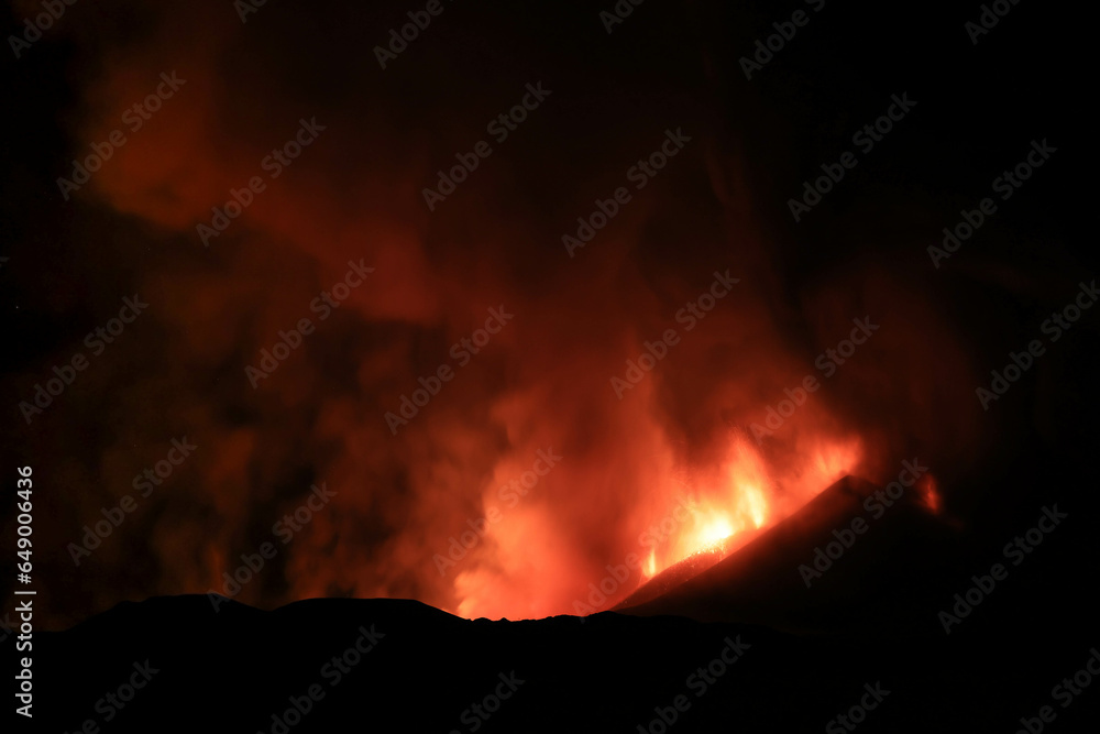 Etna panoramica di notte sul vulcano in eruzione con lava tra cenere gas e vapore nel cielo notturno dal cratere del 13 Agosto 2023	