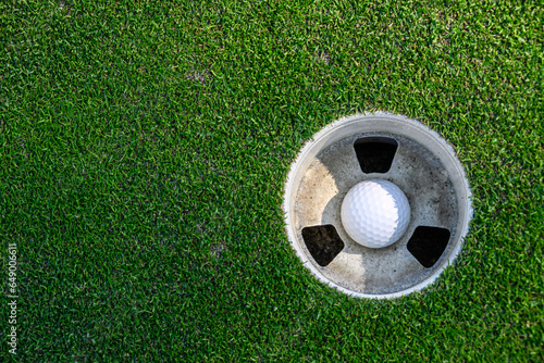 Closeup of white golf ball in the cup on a putting green 