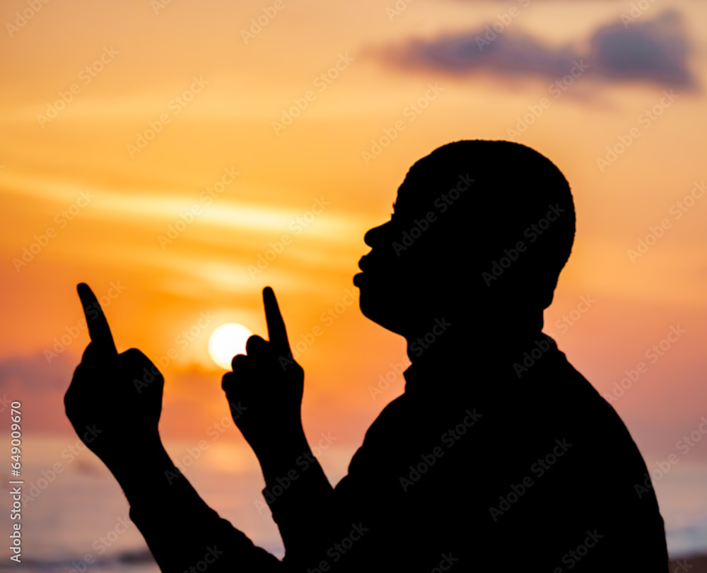 A powerful photograph capturing the silhouette of a man, his silhouette outlined by the breathtaking solstice sunset, his hands raised in adoration and gratitude to Jesus.
